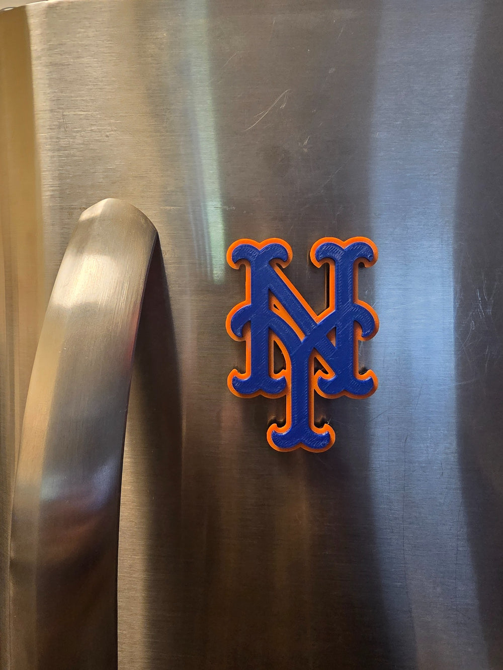 New York Logo Orange and Blue magnet on a stainless steel refrigerator