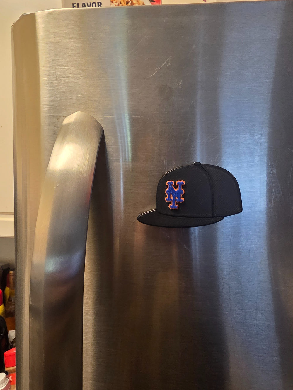New York Orange and Blue Cap magnet on a stainless steel refrigerator